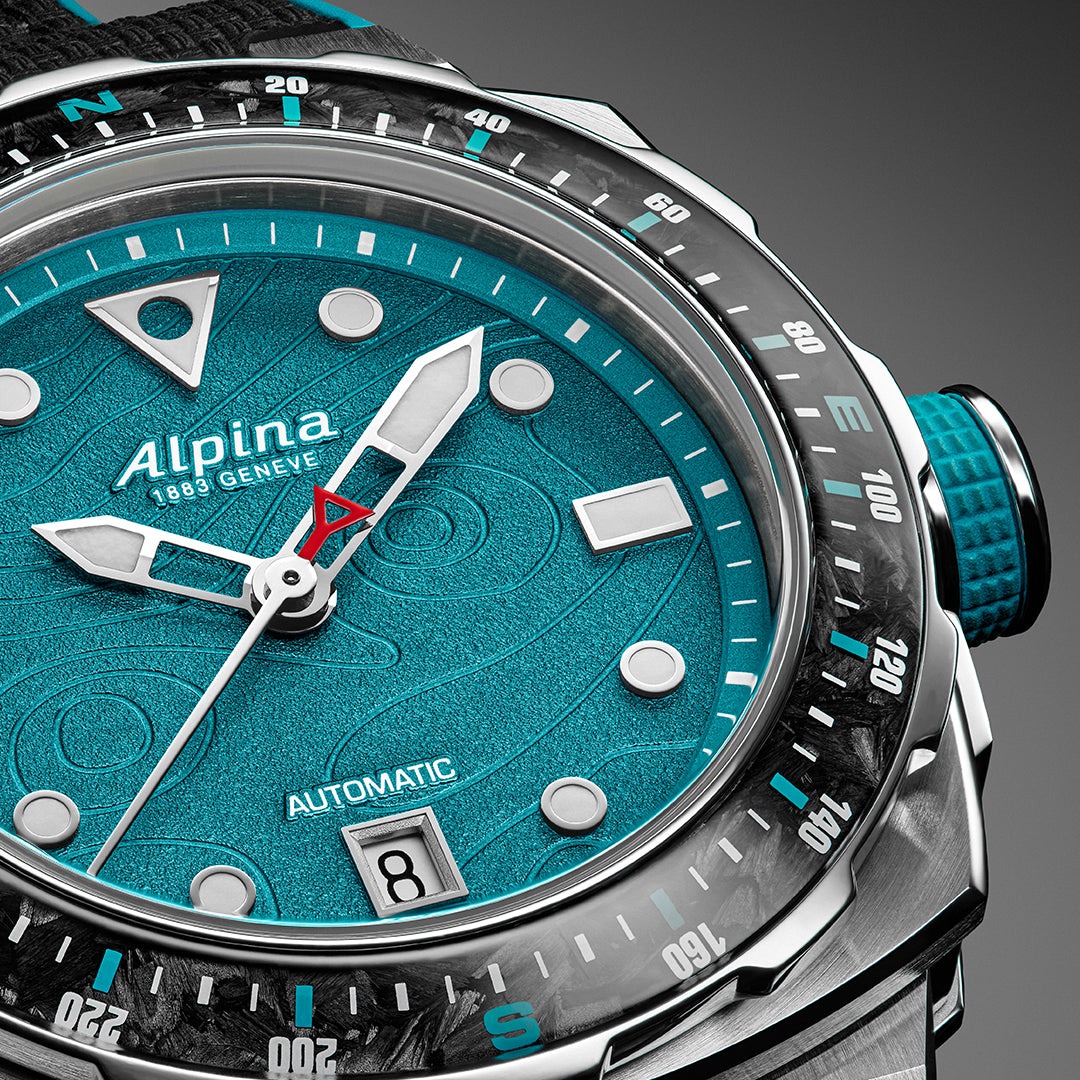 Alpina Seastrong Diver Extreme Route du Rhum, gros plan sur la lunette boussole en carbone, le cadran turquoise et la couronne vissée à grip caoutchouc turquoise