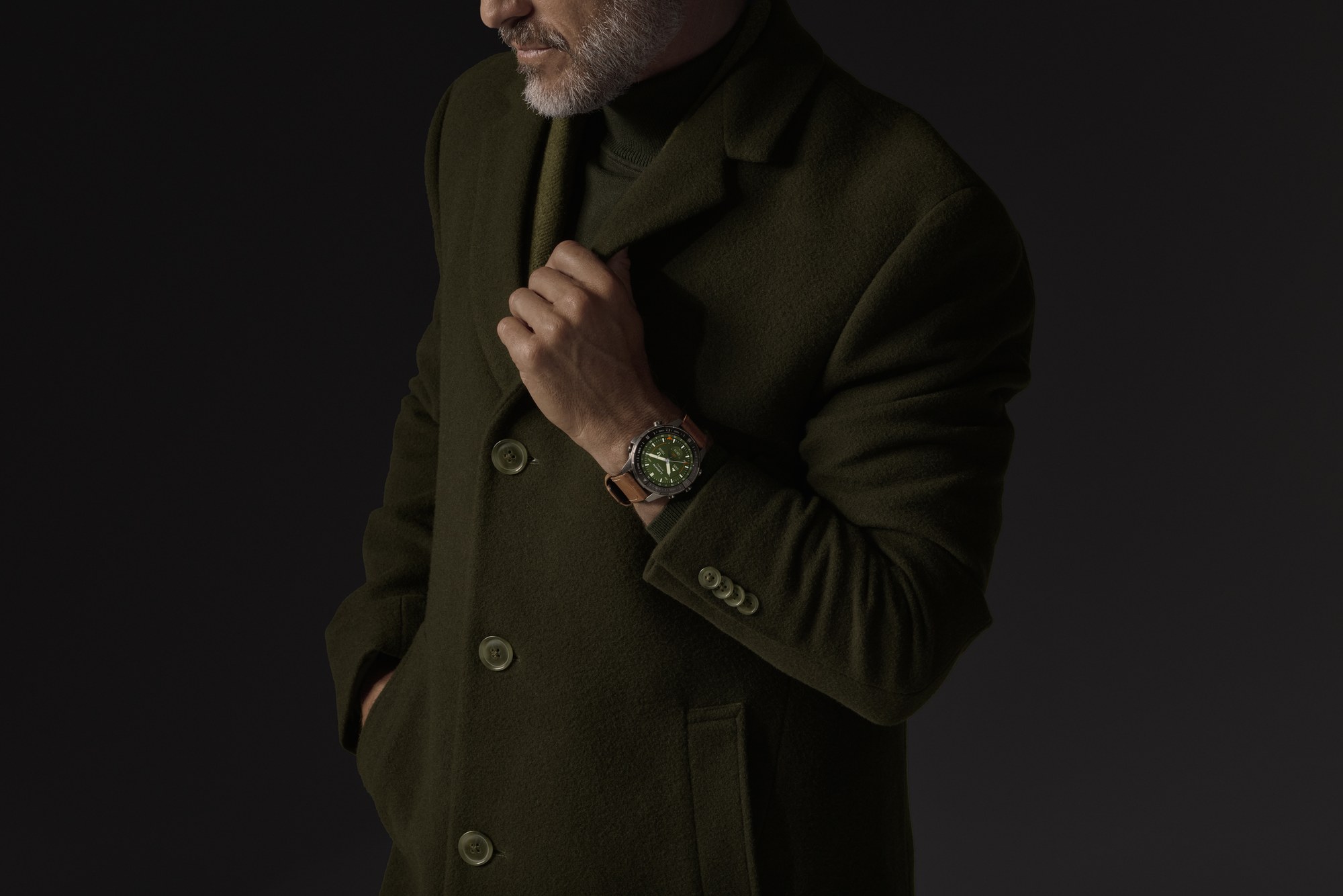Garmin MARQ Adventurer Gen 3 au poignet, cadran vert et bracelet cuir, sous un manteau de laine