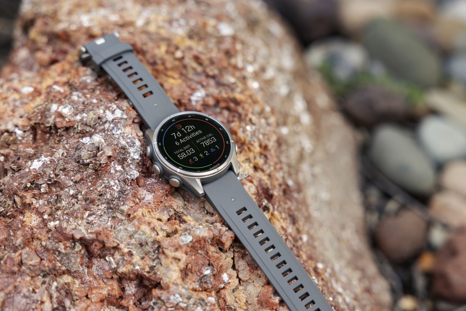 Montre Garmin fēnix posée sur un rocher rouge, résumé des activités de la semaine affiché à l'écran