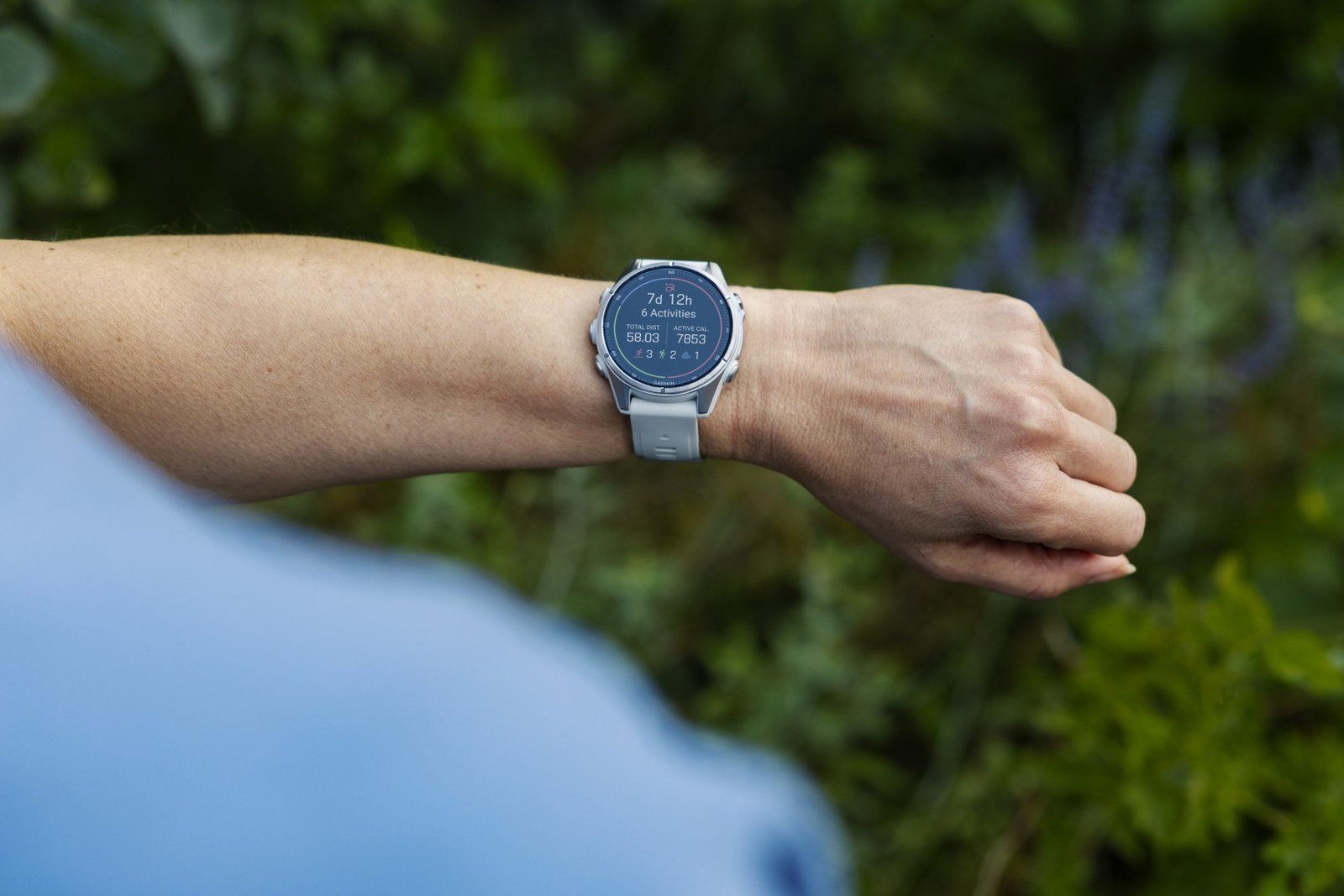 Montre Garmin fēnix au poignet en forêt, résumé des activités de la semaine affiché à l'écran