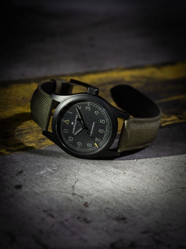 Hamilton Khaki Field Mechanical Call of Duty Modern Warfare 4 posée sur le flanc, couronne vers le haut, boîtier PVD noir sablé de 38 mm et bracelet textile kaki, visuel officiel Hamilton
