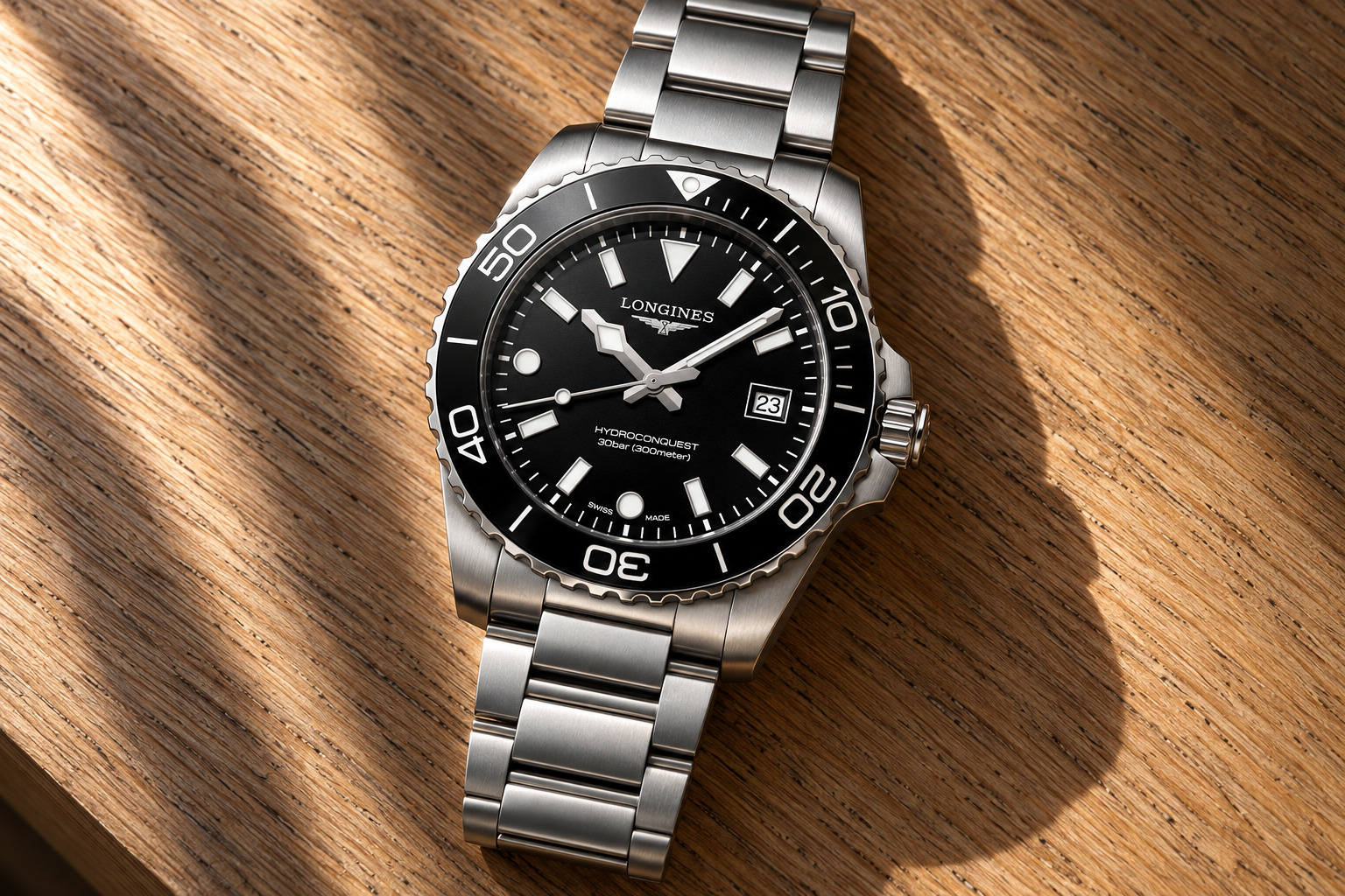 Longines HydroConquest quartz 42 mm cadran noir sablé et bracelet acier, sur du sable gris mouillé à marée basse, vue d'illustration