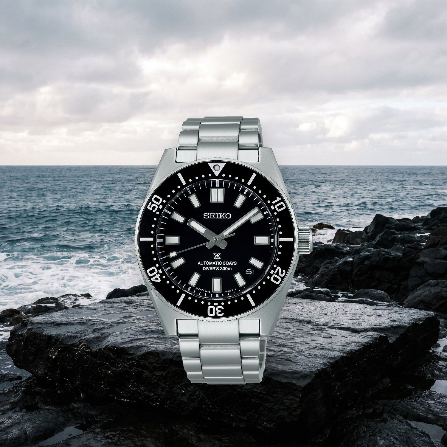 Montre Seiko Prospex 1965 Heritage Diver's SPB453J1 automatique 40 mm, cadran noir, lunette unidirectionnelle, bracelet acier, posée sur un rocher devant la mer